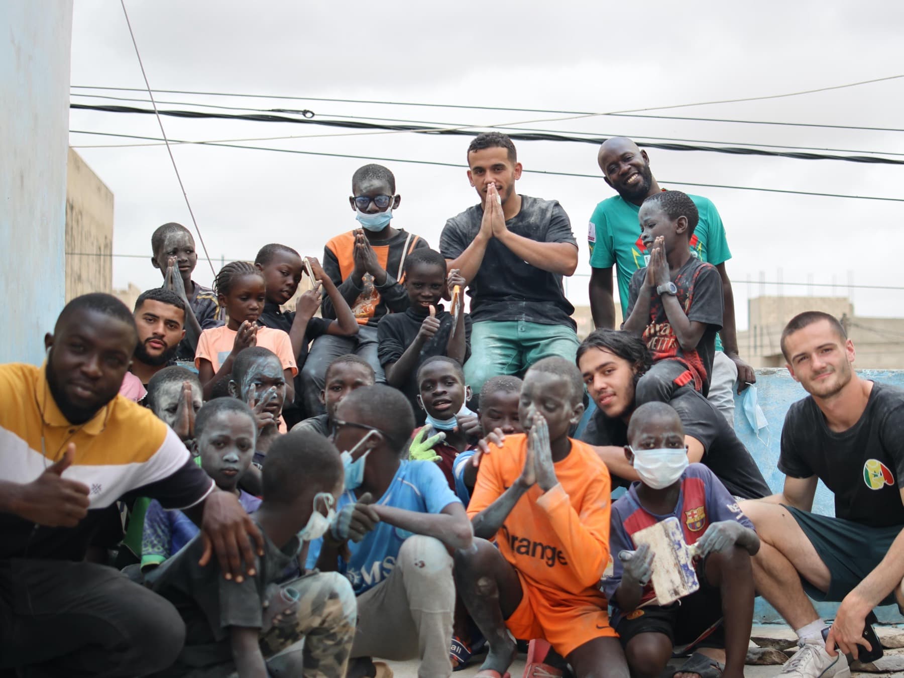 L'équipe de l'association et un groupe d'enfants réunis pour une photo, les mains jointes.