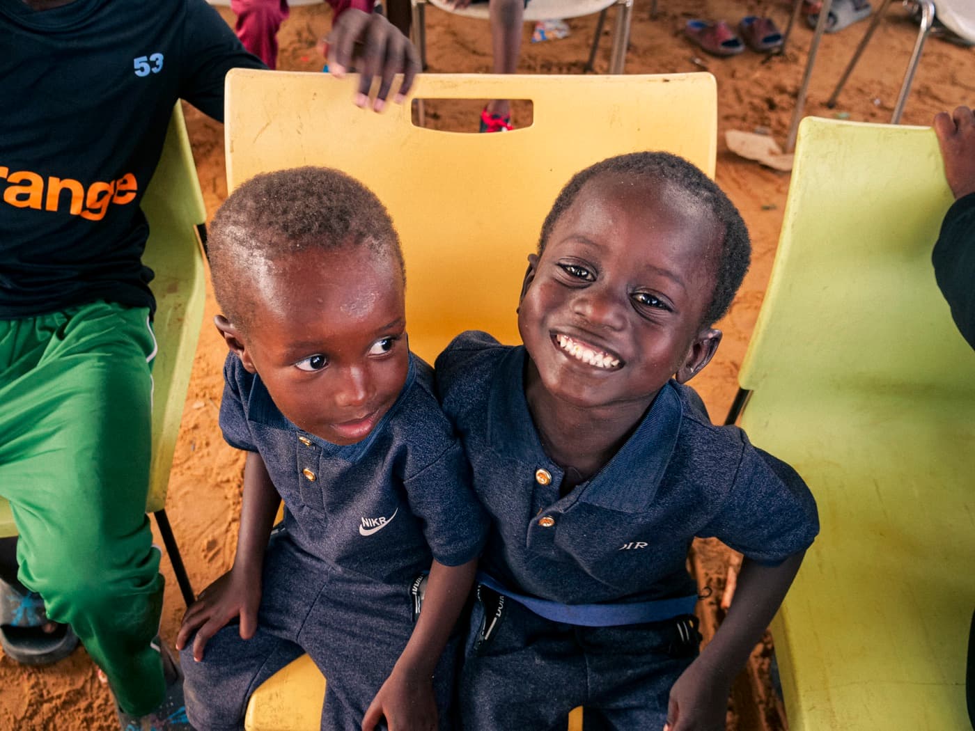 Deux jeunes frères éclatent de rire, assis dans un orphelinat partenaire.