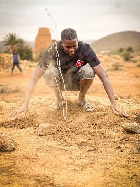 Un bénévole accroupi égalise la terre à mains nues avant la plantation.