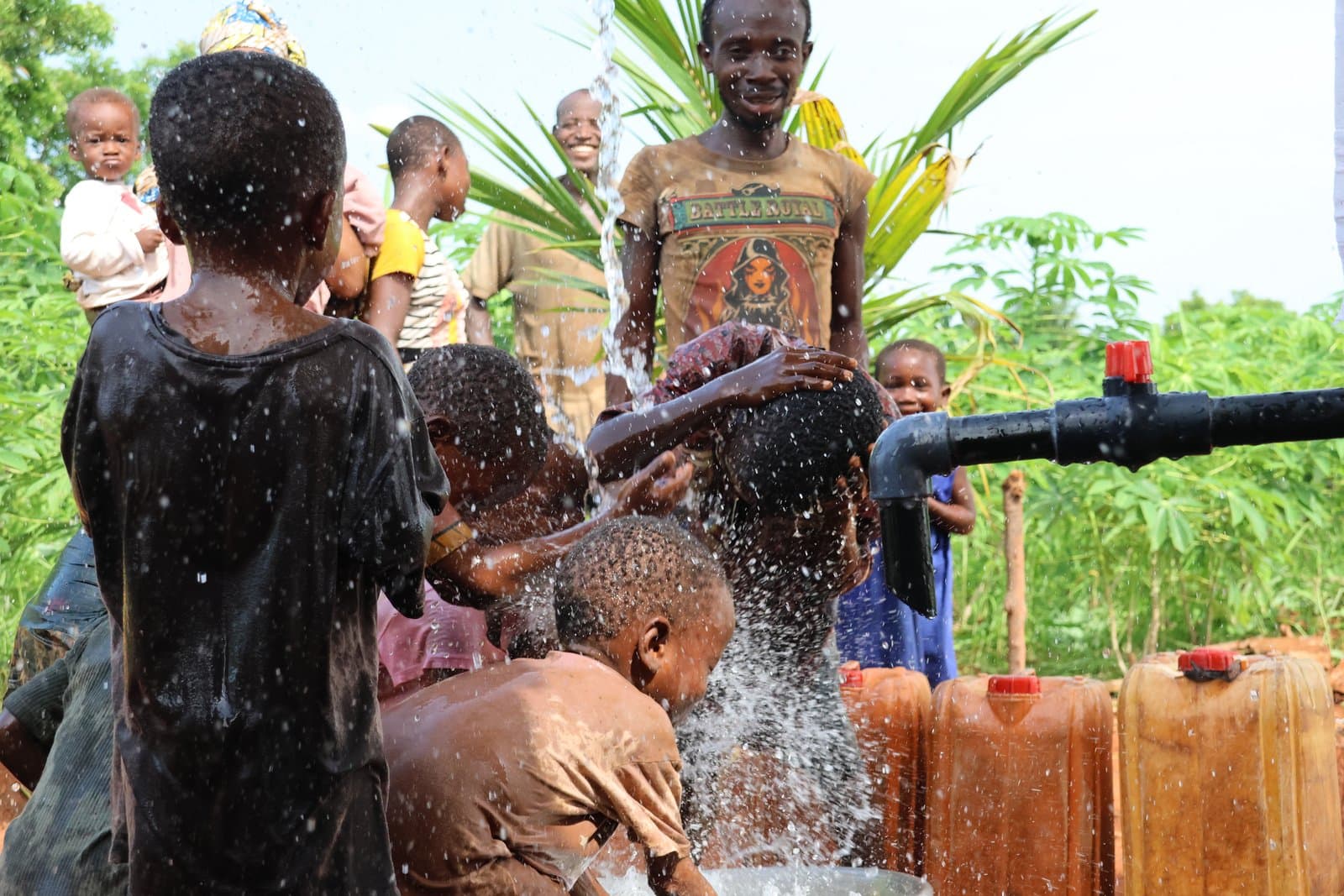 Au Togo, des enfants rient sous le jet d'eau d'un forage.