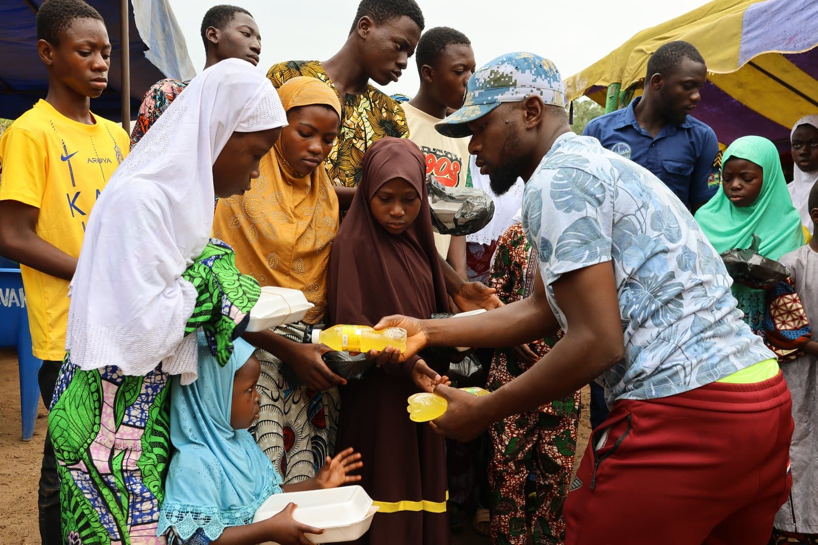 Un bénévole sert des repas aux habitants venus nombreux lors d'une distribution au Togo.