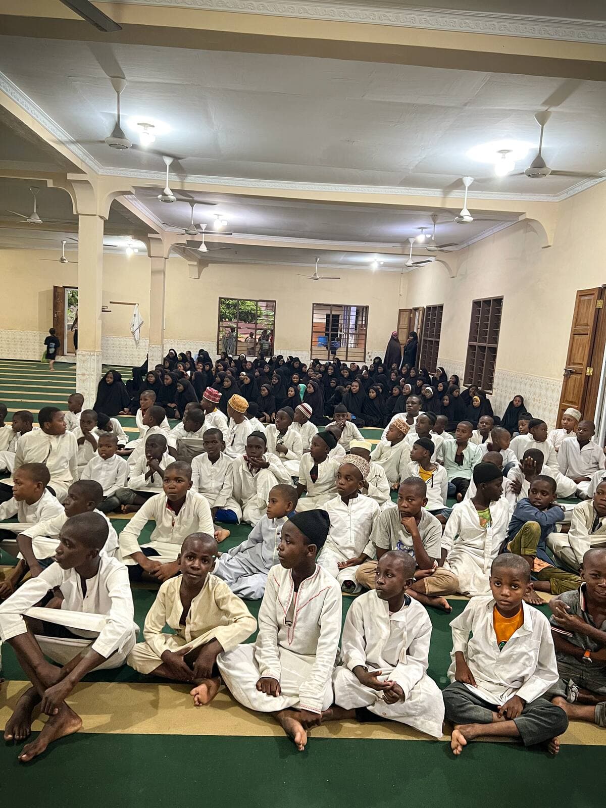 À Zanzibar, des dizaines d'enfants en tenue blanche assis sur des tapis dans la grande salle du centre.