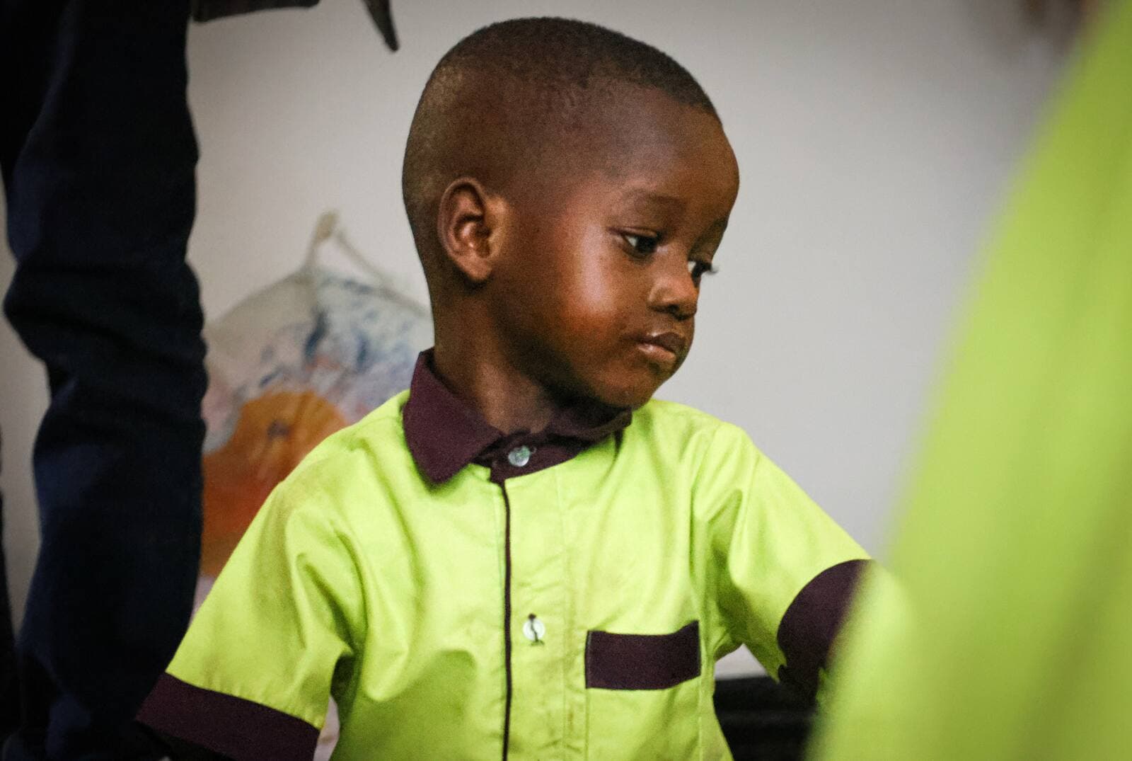 À Zanzibar, un petit élève en uniforme vert pomme baisse les yeux, concentré.
