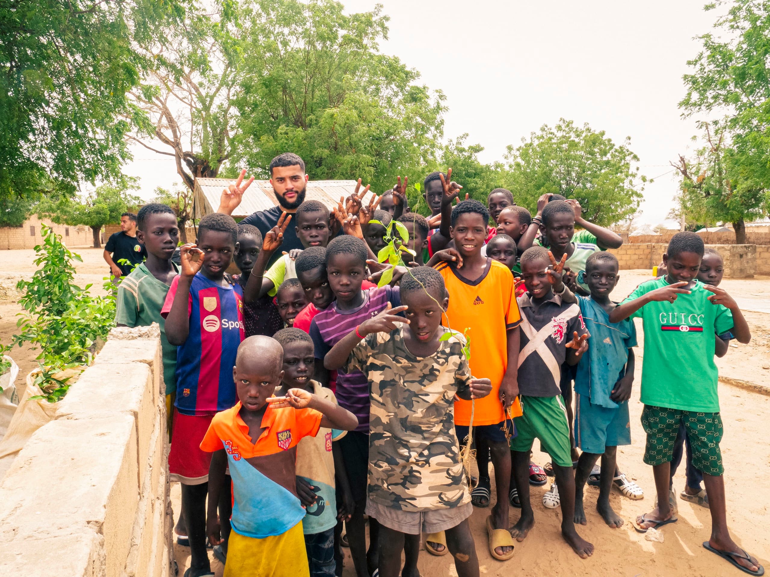 Un groupe d'enfants d'un village accueille l'équipe en souriant et en levant les bras.