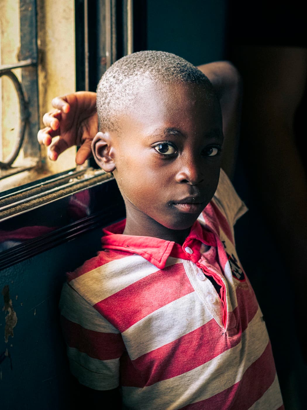 Portrait d'un enfant pensif à la fenêtre d'une maison.